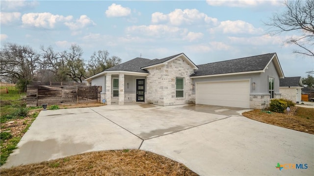 view of front of home featuring stone siding, fence, roof with shingles, concrete driveway, and an attached garage