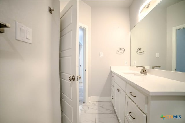 bathroom with marble finish floor, vanity, and baseboards