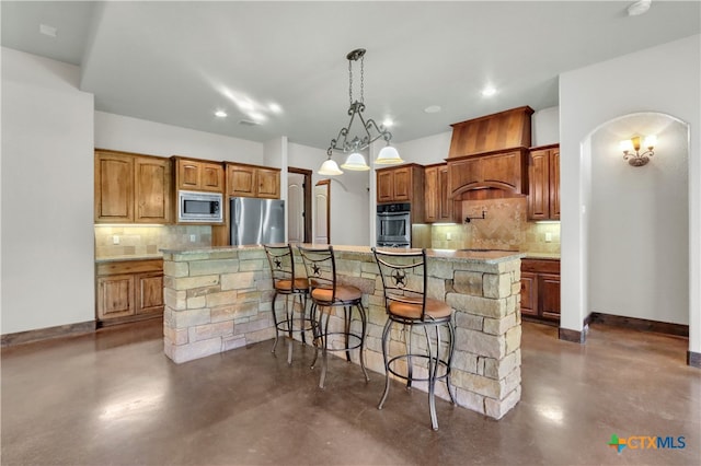 kitchen with tasteful backsplash, a center island with sink, appliances with stainless steel finishes, hanging light fixtures, and a breakfast bar