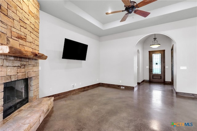 unfurnished living room with a stone fireplace and ceiling fan