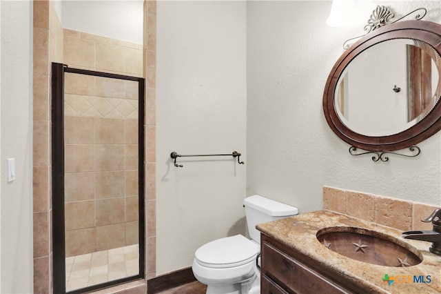 bathroom featuring toilet, vanity, and an enclosed shower