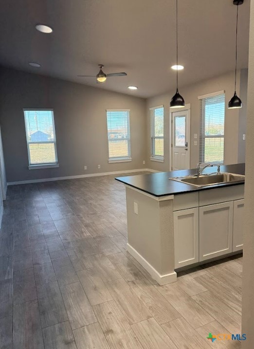 kitchen featuring ceiling fan, sink, lofted ceiling, decorative light fixtures, and white cabinets