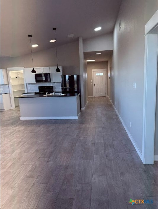 kitchen with lofted ceiling, black appliances, hanging light fixtures, decorative backsplash, and white cabinetry