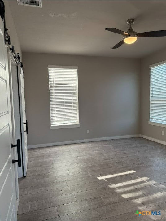 empty room with a barn door and ceiling fan