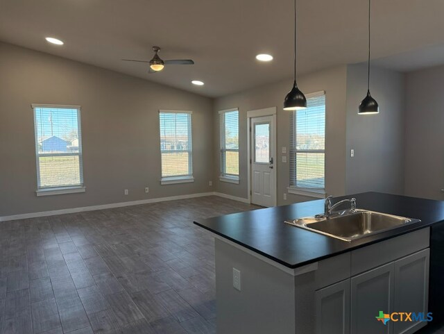 kitchen with ceiling fan, sink, vaulted ceiling, decorative light fixtures, and a kitchen island with sink