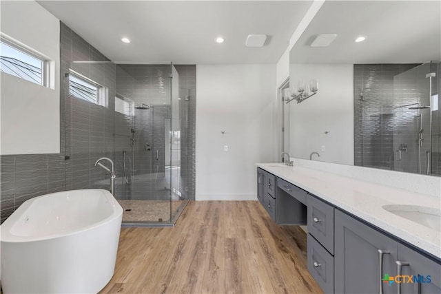 105 Gillespie Ct, Horseshoe Bay, TX 78657 - full bath with double vanity, a stall shower, wood finished floors, a freestanding tub, and recessed lighting