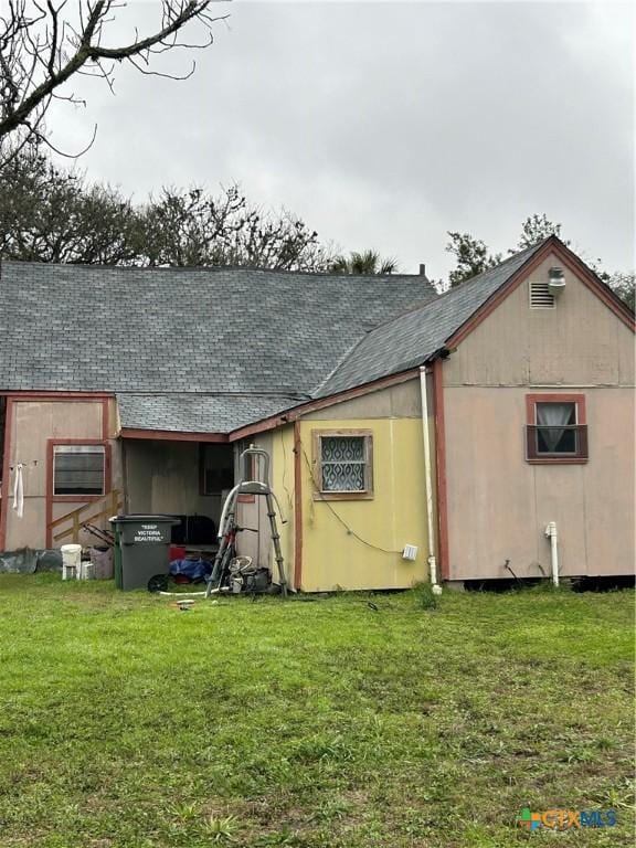 exterior space featuring roof with shingles and a lawn