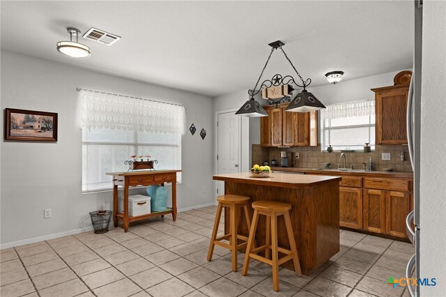 1712 Indian Camp Trl, Copperas Cove, TX 76522 - kitchen with brown cabinets, decorative backsplash, a kitchen island, and light tile patterned floors