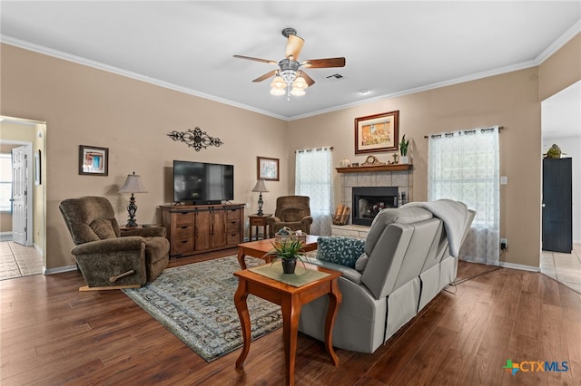 1712 Indian Camp Trl, Copperas Cove, TX 76522 - living room with a ceiling fan, wood-type flooring, a tiled fireplace, and ornamental molding