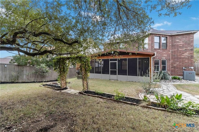 back of house featuring a lawn, central AC unit, and a sunroom