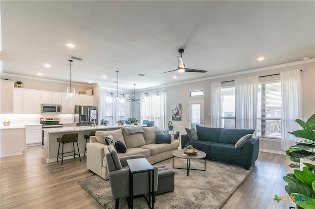 living room with crown molding, recessed lighting, visible vents, ceiling fan, and light wood-type flooring