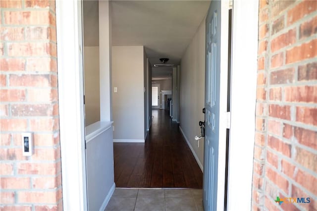 hall with hardwood / wood-style floors and brick wall