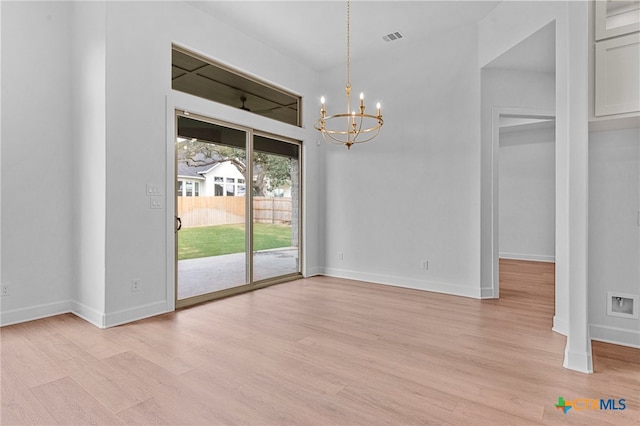 unfurnished dining area with a notable chandelier and light hardwood / wood-style flooring