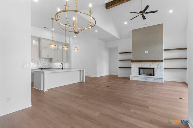 unfurnished living room featuring a fireplace, light hardwood / wood-style floors, and high vaulted ceiling