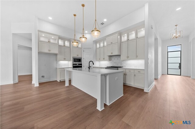 kitchen with appliances with stainless steel finishes, hanging light fixtures, a center island with sink, and dark hardwood / wood-style floors