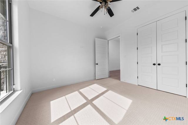 unfurnished bedroom with light carpet, ceiling fan, and a closet