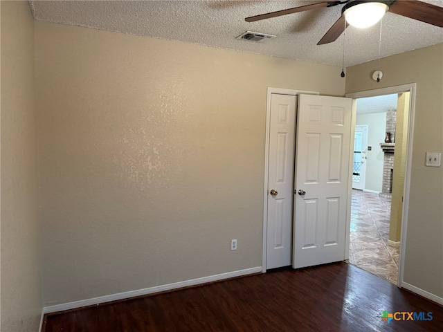 spare room with ceiling fan, a textured ceiling, and dark hardwood / wood-style flooring