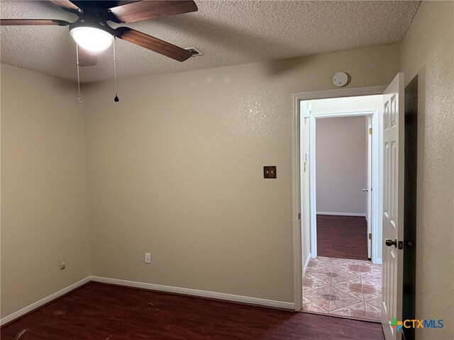 unfurnished room with dark wood-type flooring, ceiling fan, and a textured ceiling