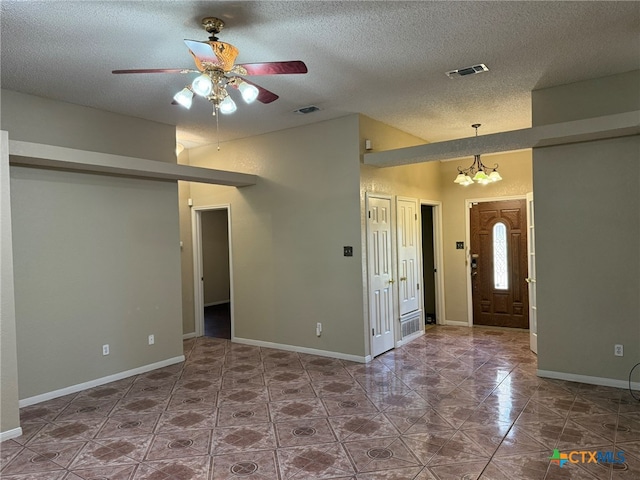 entrance foyer with ceiling fan with notable chandelier, a textured ceiling, and lofted ceiling