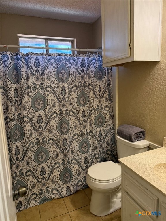 bathroom with toilet, vanity, a textured ceiling, and tile patterned floors