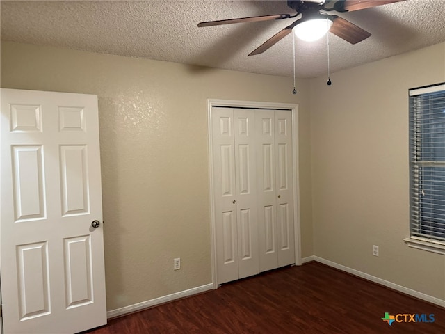 unfurnished bedroom with dark wood-type flooring, a closet, a textured ceiling, and ceiling fan