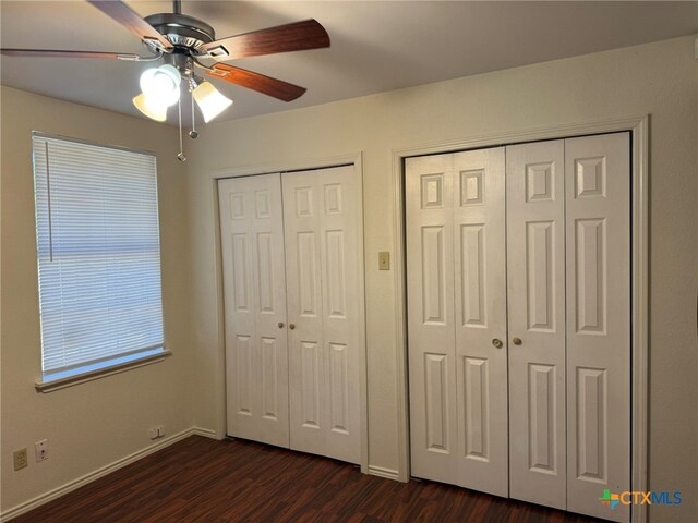 unfurnished bedroom with multiple closets, dark wood-type flooring, and ceiling fan