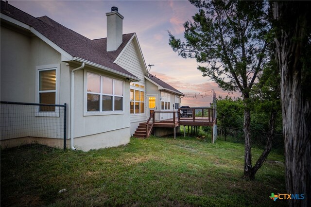 1882 Rush Crk, Canyon Lake, TX 78133 - back of property at dusk with a chimney, a shingled roof, and a deck