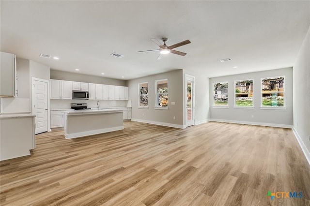 kitchen with a center island, white cabinets, light hardwood / wood-style floors, and appliances with stainless steel finishes