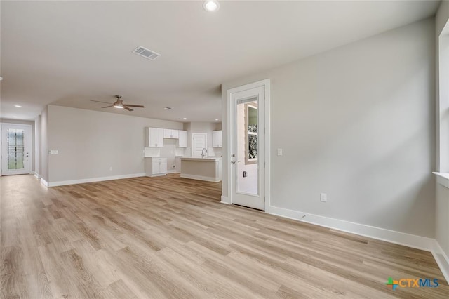 unfurnished living room with ceiling fan, sink, and light hardwood / wood-style flooring