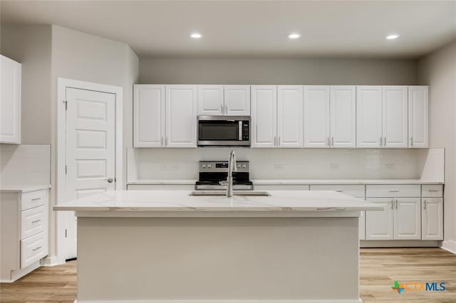 kitchen featuring a center island with sink, sink, light hardwood / wood-style floors, white cabinetry, and stainless steel appliances