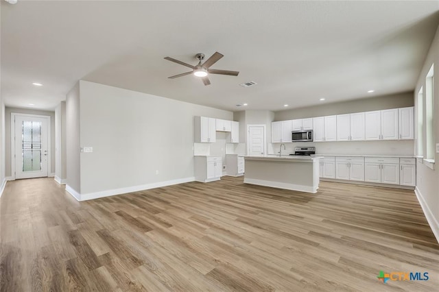 unfurnished living room featuring light hardwood / wood-style flooring, ceiling fan, and sink