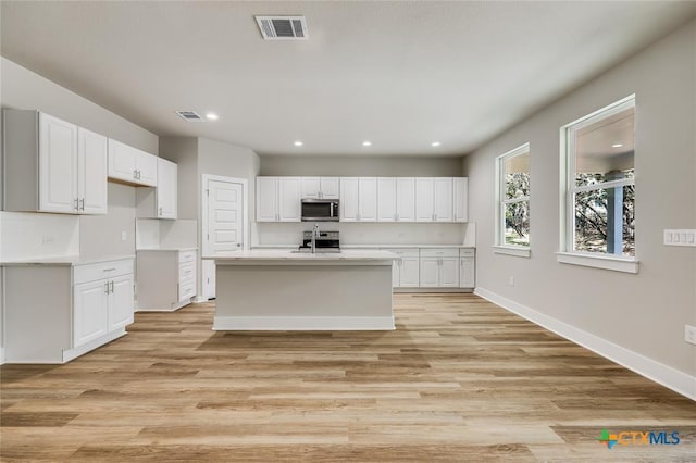 kitchen featuring white cabinets, stainless steel appliances, light hardwood / wood-style floors, and sink