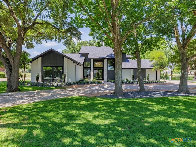 3415 Chisholm Trl, Salado, TX 76571 - mid-century home featuring a front lawn, a shingled roof, stucco siding, and curved driveway