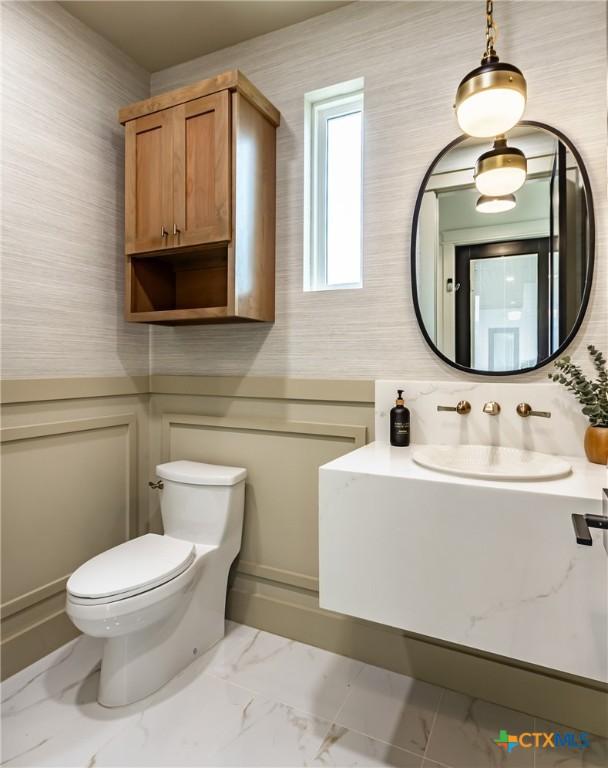 bathroom with marble finish floor, vanity, and toilet