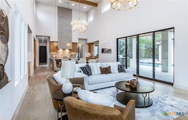 living area featuring a chandelier, light wood-style flooring, and baseboards