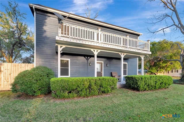 view of front of property featuring a balcony and a front yard