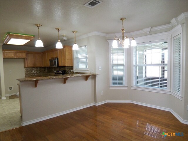 kitchen with pendant lighting, kitchen peninsula, hardwood / wood-style floors, and ornamental molding