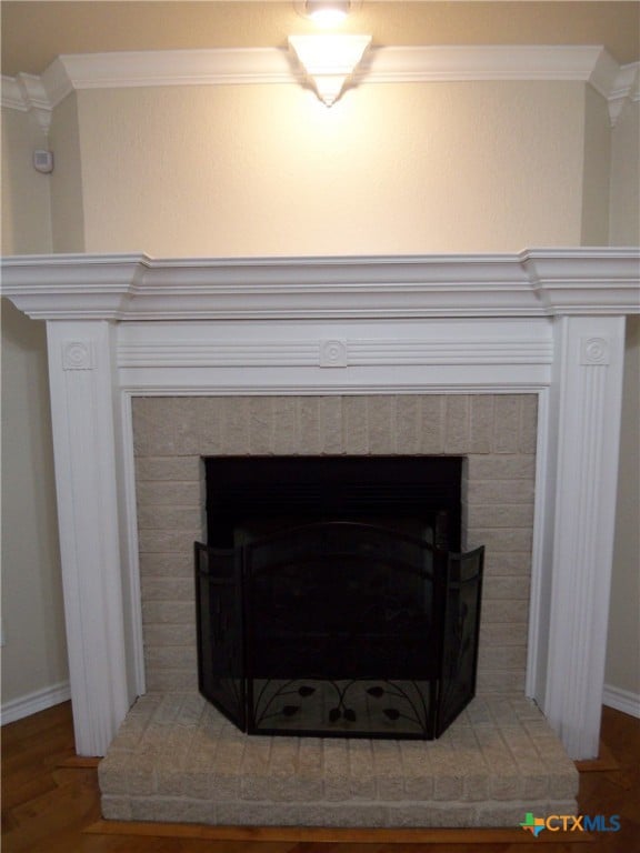 room details featuring a brick fireplace, crown molding, and hardwood / wood-style floors