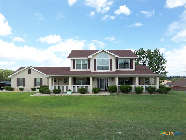 colonial-style house featuring a porch and a front yard