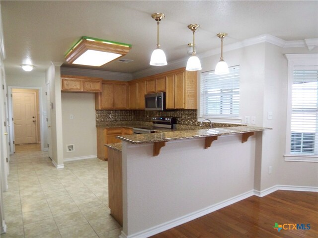 kitchen with light hardwood / wood-style floors, decorative light fixtures, range, crown molding, and decorative backsplash