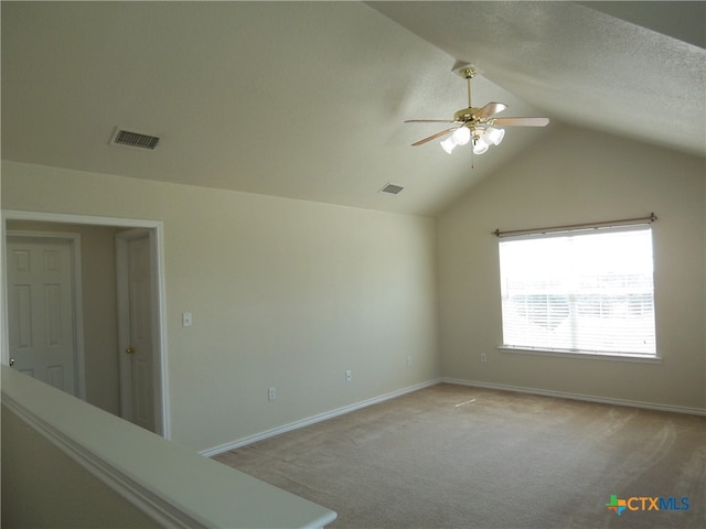 empty room featuring ceiling fan, a textured ceiling, light carpet, and lofted ceiling