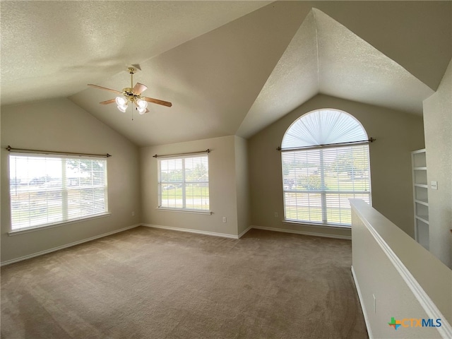 carpeted spare room with lofted ceiling, a textured ceiling, and ceiling fan