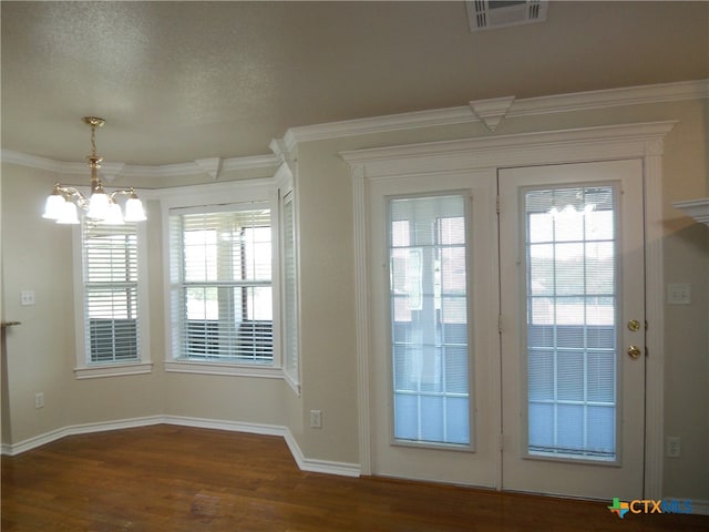 doorway featuring dark wood-type flooring, a textured ceiling, crown molding, and a notable chandelier