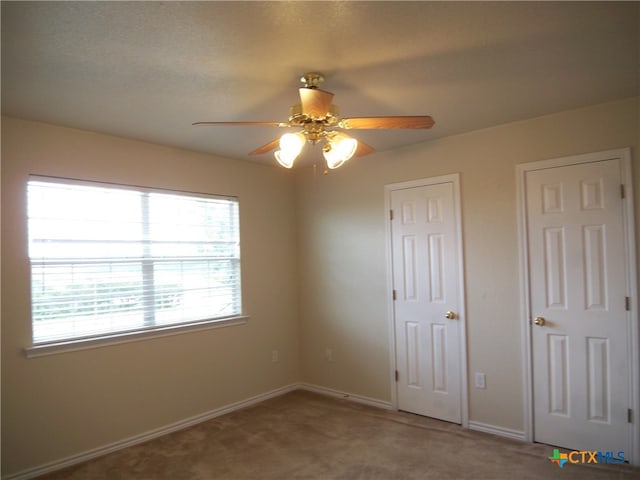 unfurnished bedroom with carpet floors, ceiling fan, and two closets