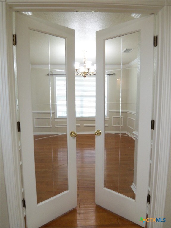 doorway to outside featuring french doors, wood-type flooring, and an inviting chandelier