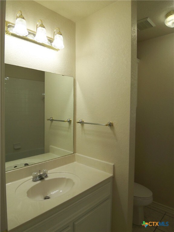 bathroom with tile patterned flooring, vanity, and toilet