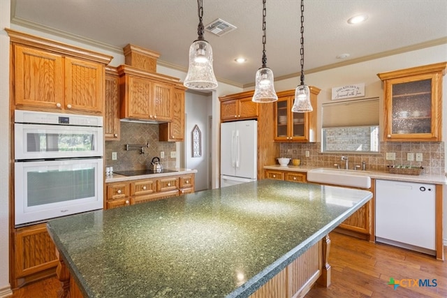 kitchen featuring crown molding, a kitchen island, sink, dark wood-type flooring, and white appliances