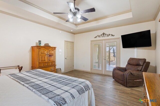 bedroom with french doors, wood-type flooring, access to exterior, a tray ceiling, and ceiling fan