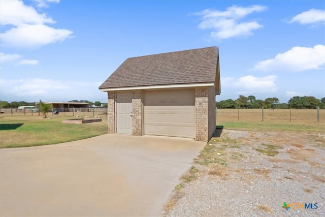 garage with a rural view and a yard