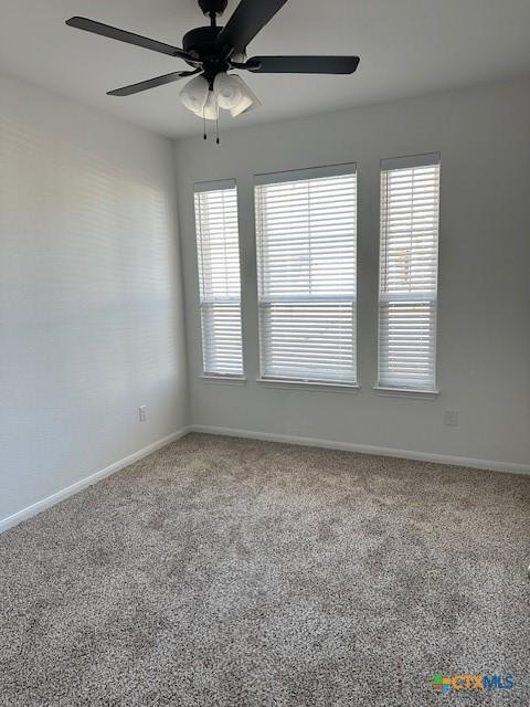 carpeted empty room with ceiling fan and baseboards